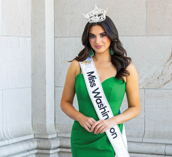 Une femme se tient les bras croisés à côté d’une fenêtre